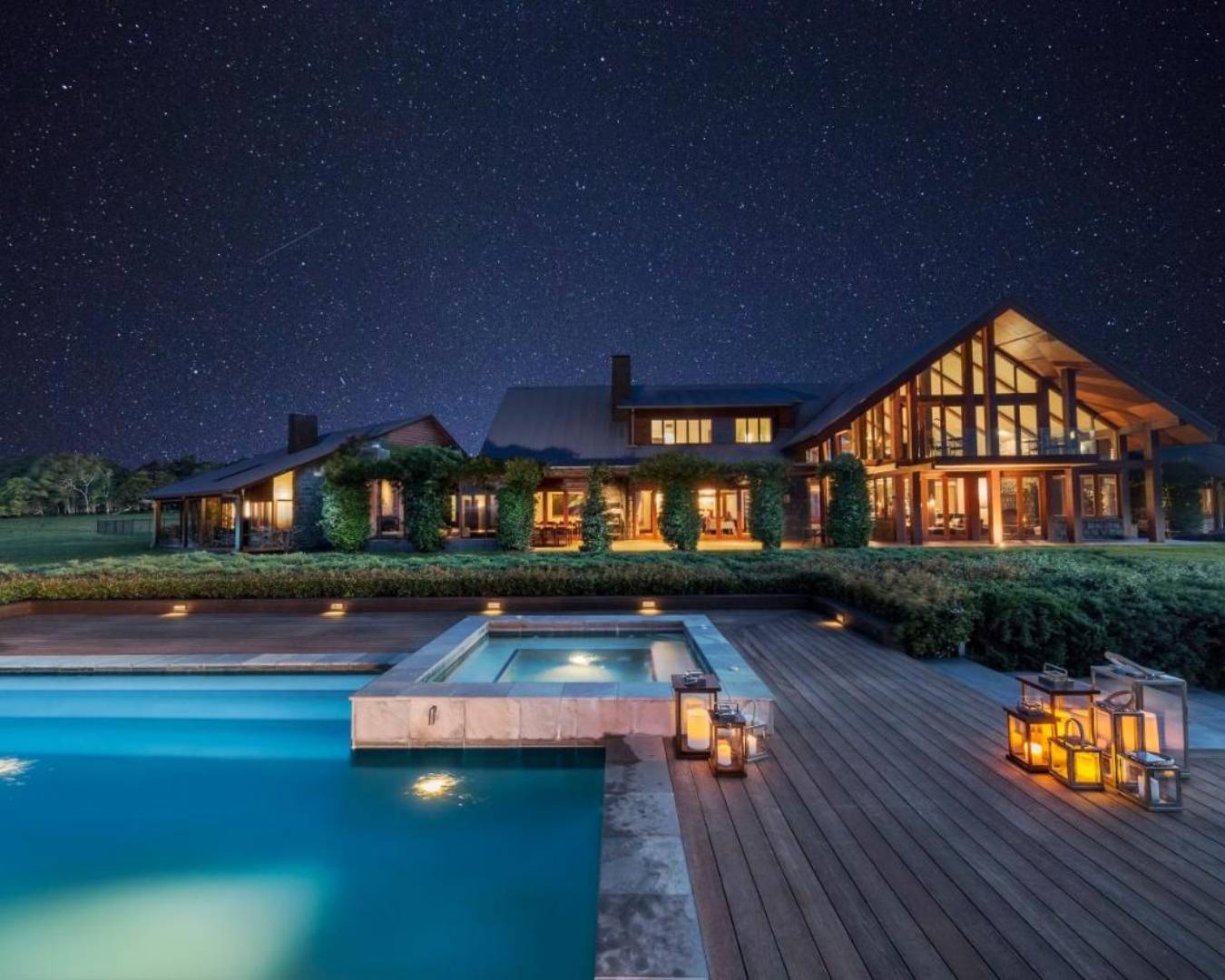 exterior of luxurious house and pool at night time