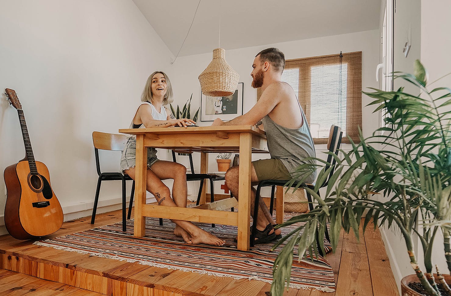 Two people sit at a dining room table.
