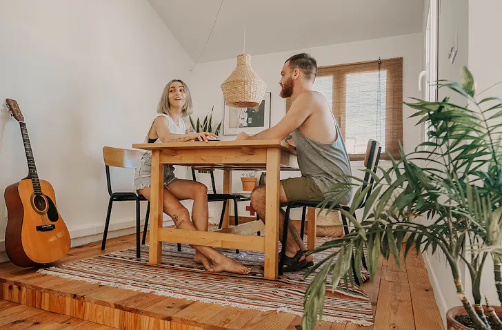 Two people sit at a dining room table.