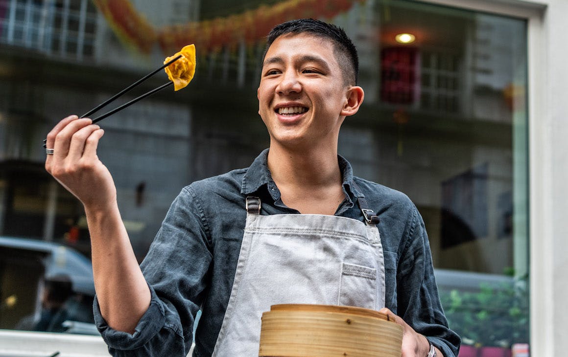 Brendan Pang holds up dumpling with chopsticks