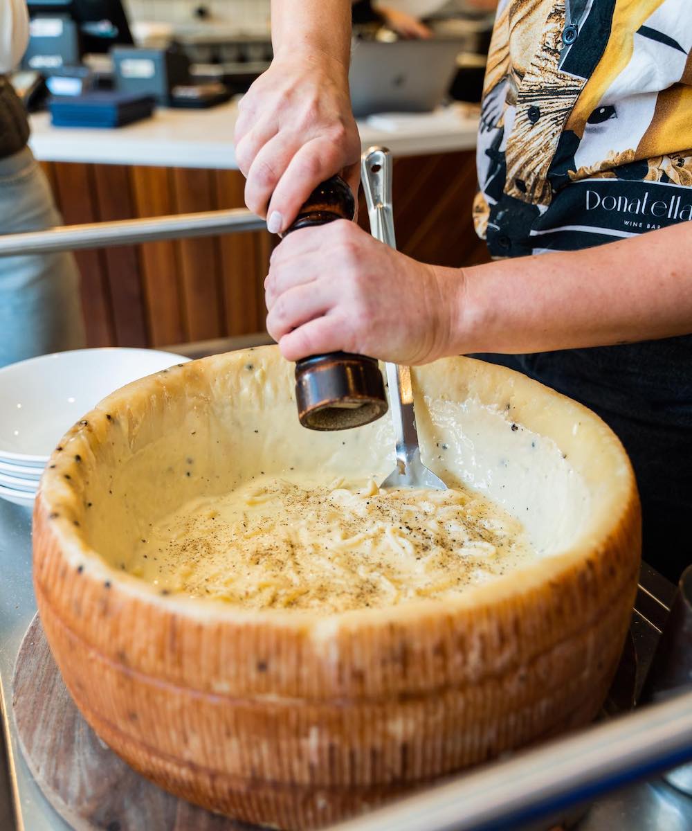 A giant cheese wheel filled with pasta