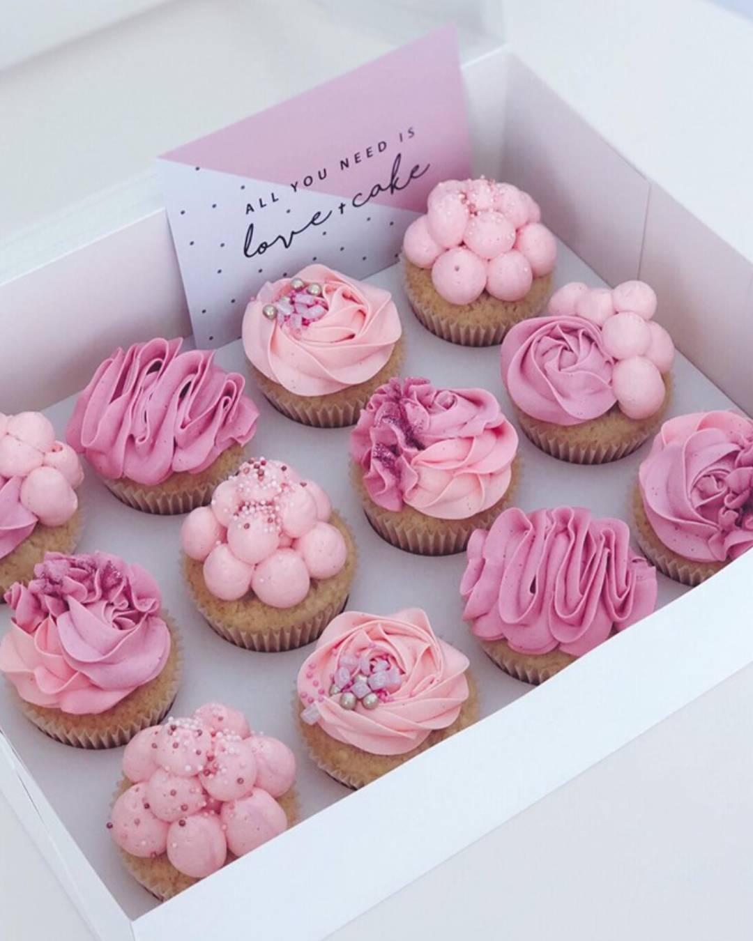 pink icing covered cupcakes sitting in box