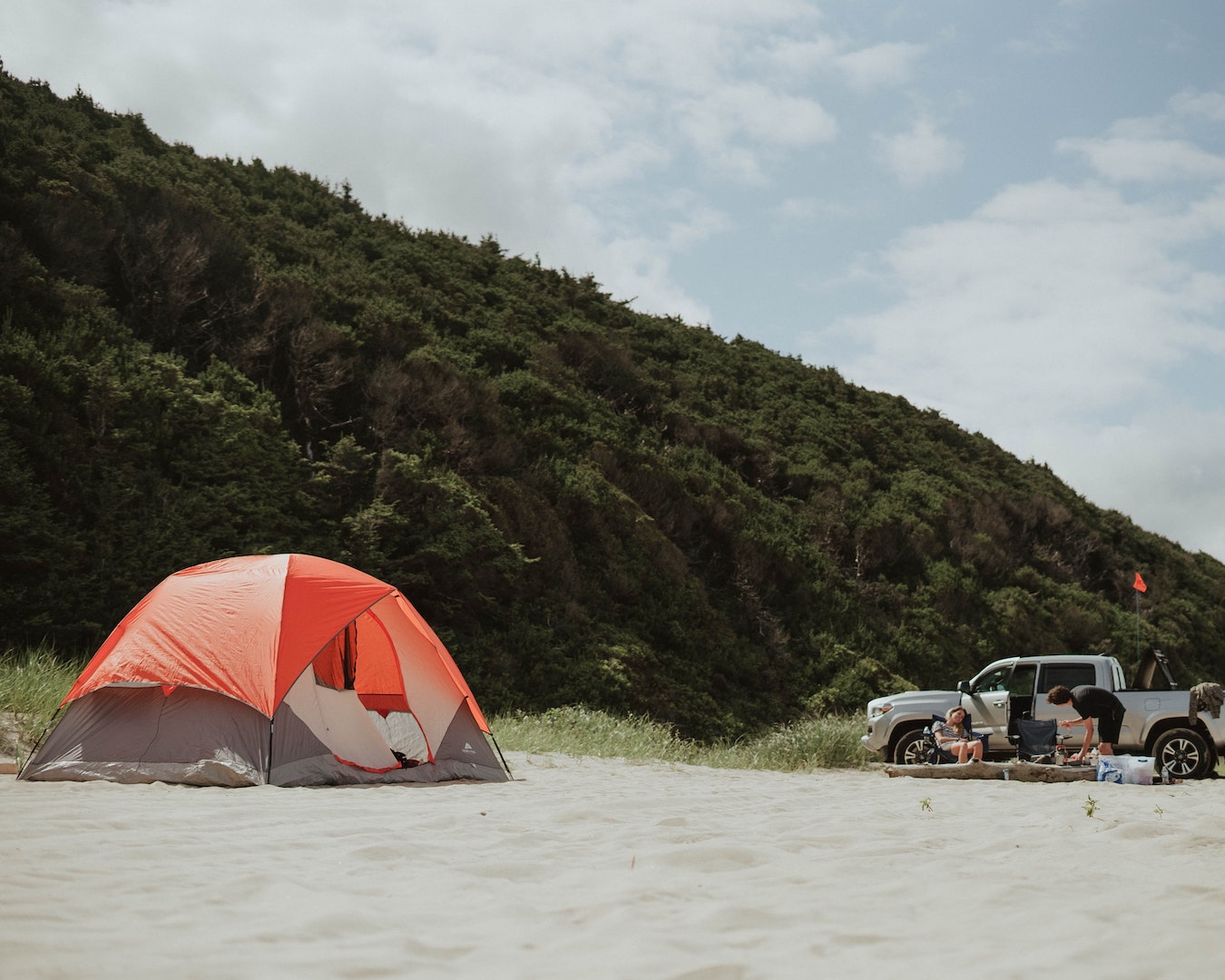 A Queensland beach campsite with an orange tent and large ute.