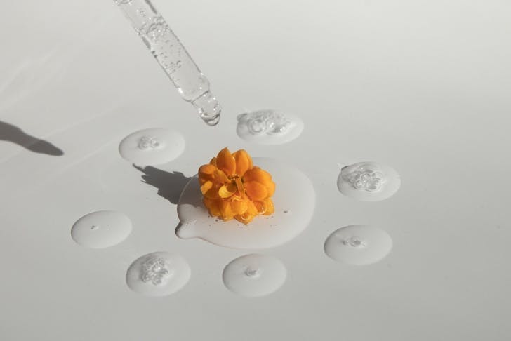 A series of drops of essential oil with an orange flower in the centre.