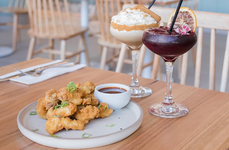 a plate of karaage chicken and two cocktails