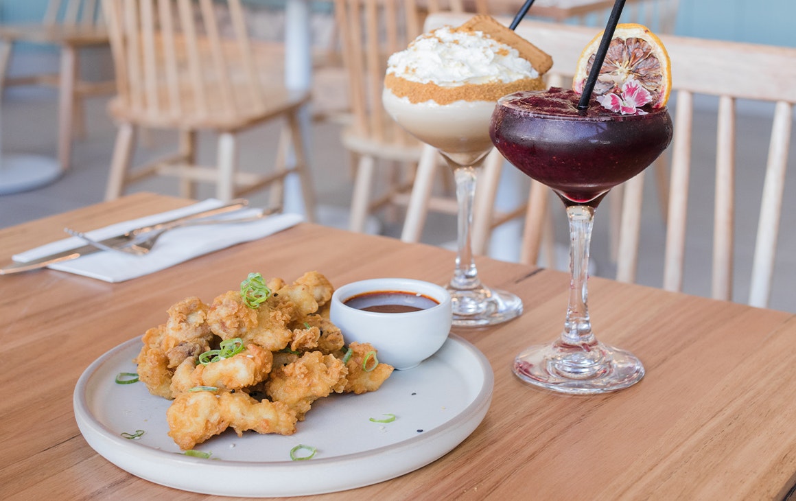 a plate of karaage chicken and two cocktails