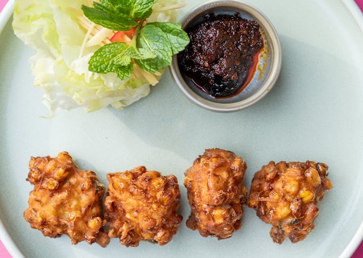 a plate of corn fritters with lettuce and sauce