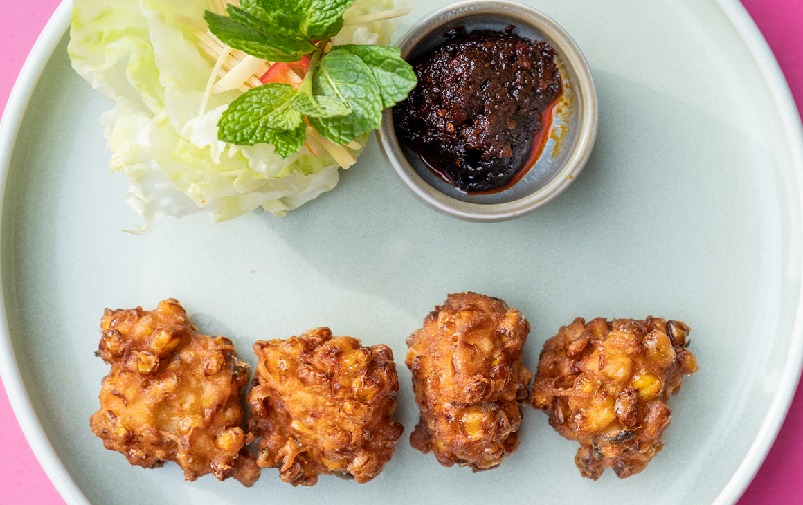 a plate of corn fritters with sauce and lettuce