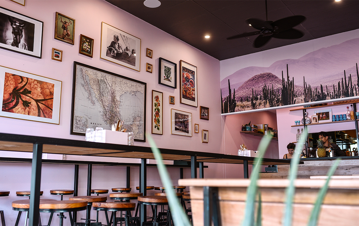 a pink restaurant interior with framed images on the walls