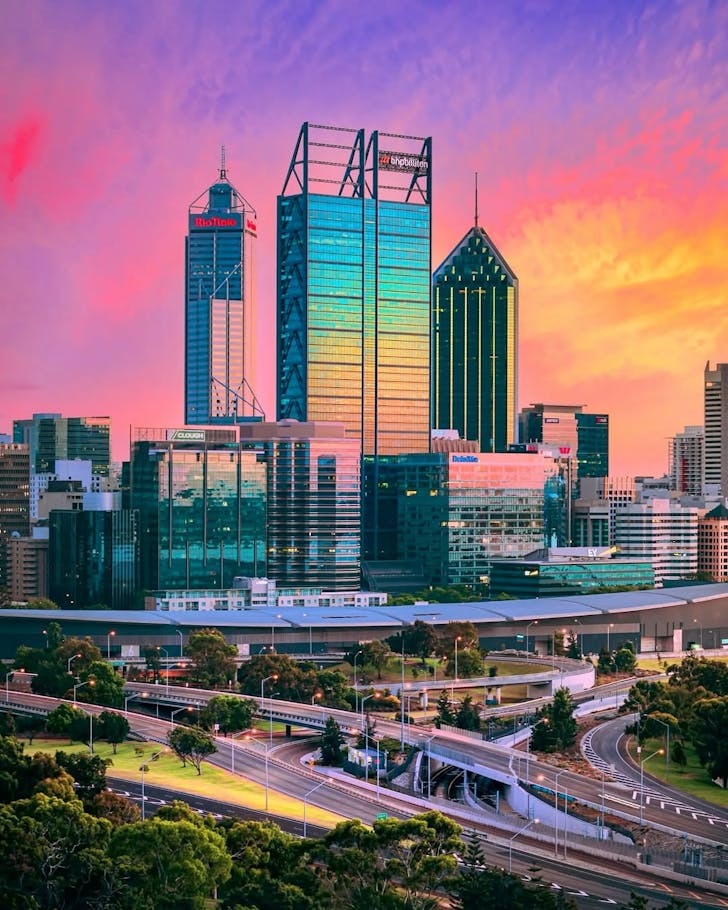 The city skyline of Perth lit up in rainbow colours by the sunset