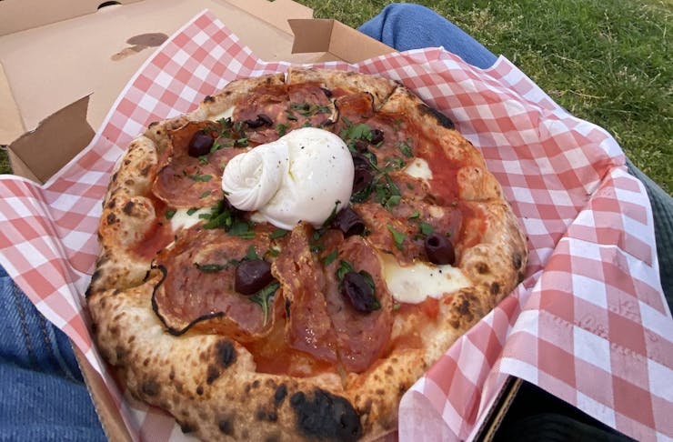 a takeaway pizza topped with burrata