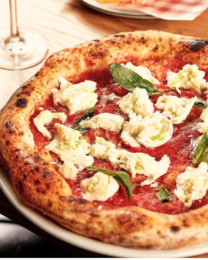 A pizza on a tabletop with fresh mozzarella and basil