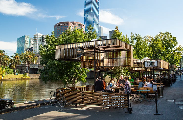 An open air bar by the river drenched in sunlight.