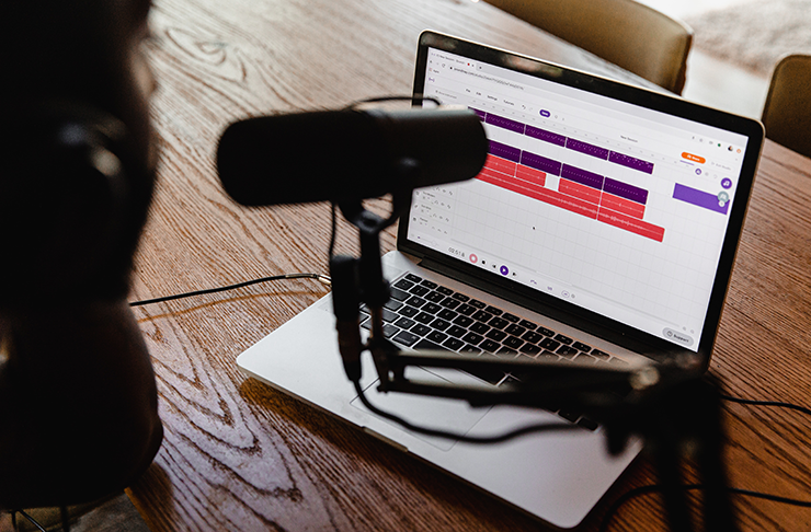 A person talking into a microphone in front of their computer.