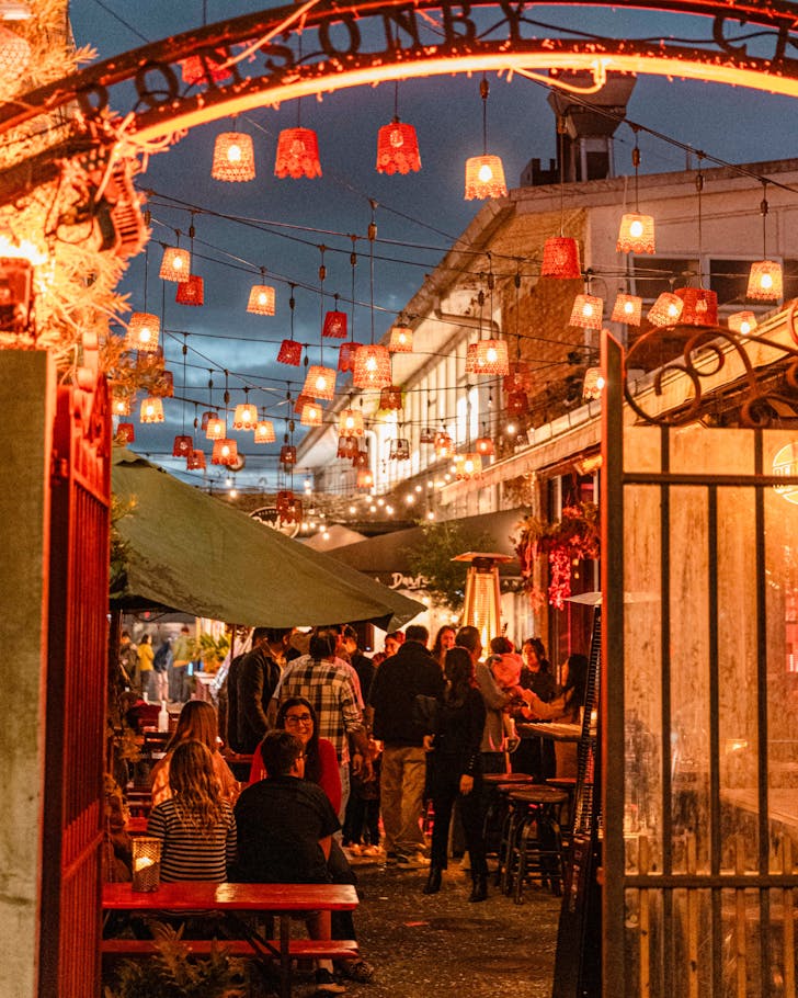 An illuminated, lantern-laden view of Ponsonby Central's laneways through their red side gates