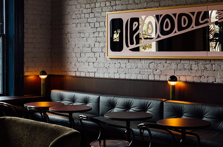 A luxe restaurant interior with a rectangular mirror on the wall. Text on the mirror reads 'Poodle'.