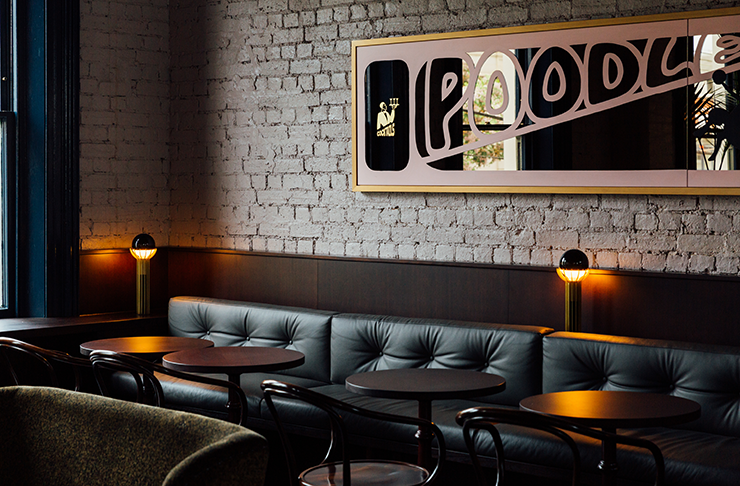 A luxe restaurant interior with a rectangular mirror on the wall. Text on the mirror reads 'Poodle'.