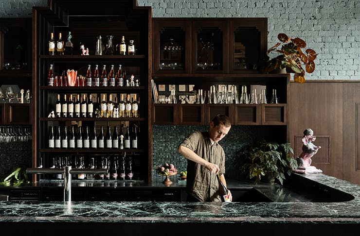 A man serving a cocktail on a granite bar.