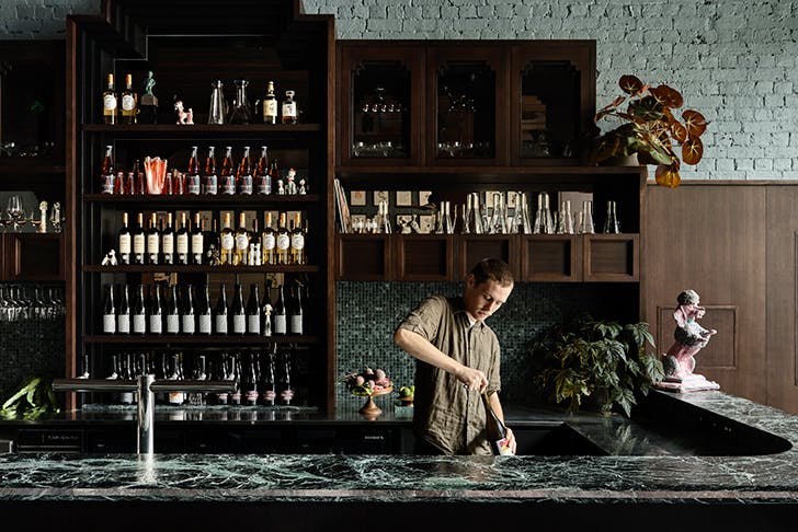 A man serving a cocktail on a granite bar.