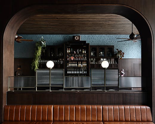 A long brown leather seat between two pillars. Poodle's bar can be seen in the background.