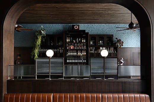 A long brown leather seat between two pillars. Poodle's bar can be seen in the background.