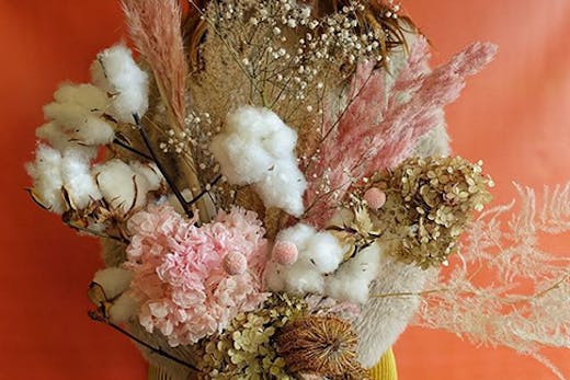 A stunning dried flower arrangement in front of a multicoloured background.