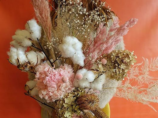 A stunning dried flower arrangement in front of a multicoloured background.