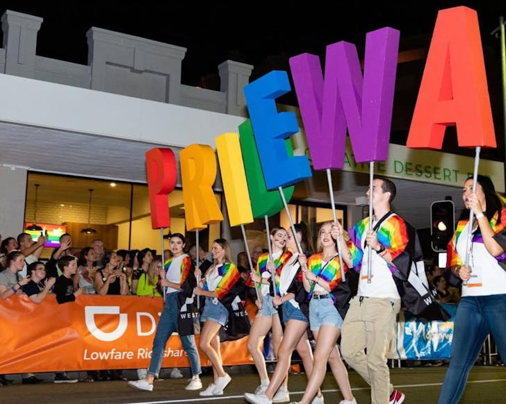 A group of people walk in the Perth Pride parade, holding letters that spell out Pride WA