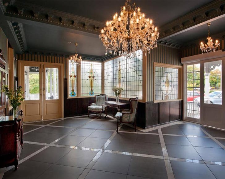 A swish, historic foyer of a hotel with stunning chandelier. 