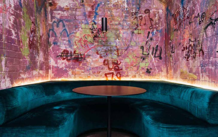 a green booth lounge with a bright graffiti wall behind it