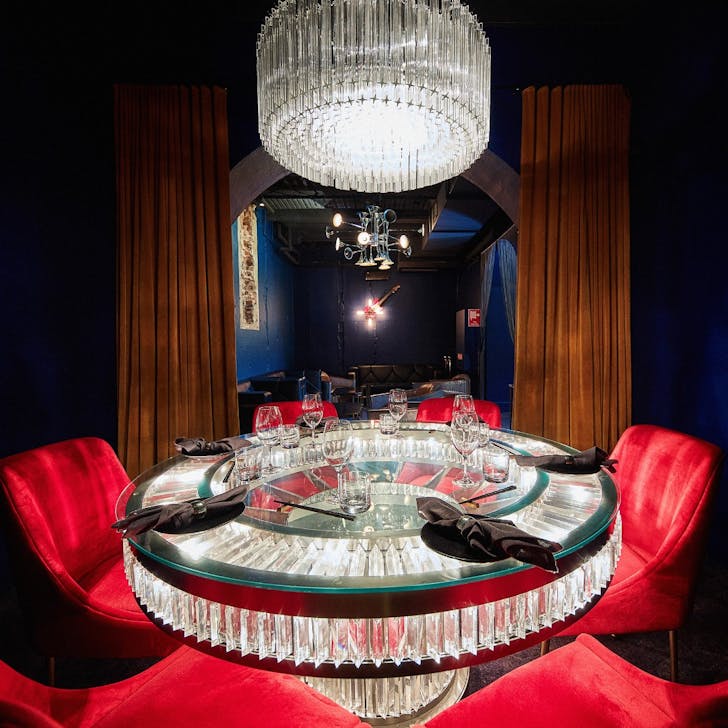 a small room with a glass table and red chairs
