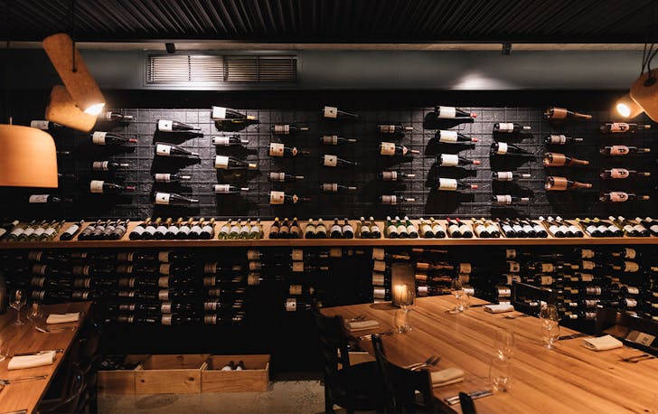 a dining room with a wall lined with wine bottles