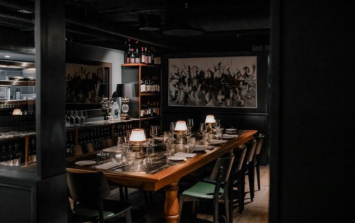 a dimly lit dining room with a large table adorned with lamps