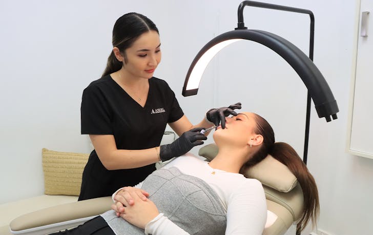 a beauty technician injecting a patient in the chin