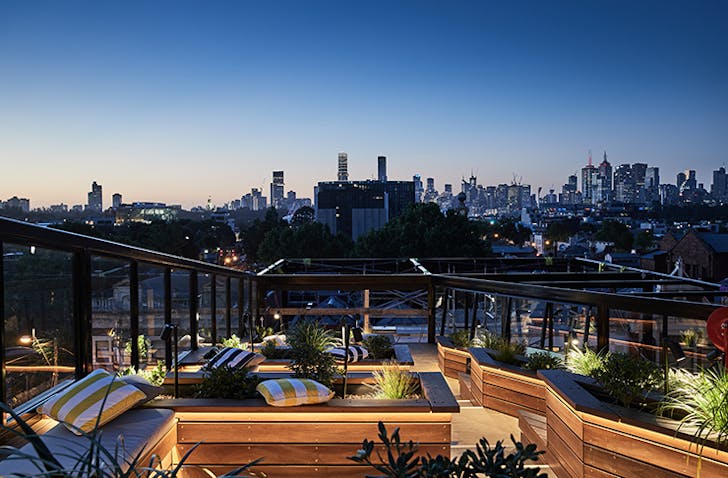 A fancy rooftop bar overlooking the Melbourne skyline at night.