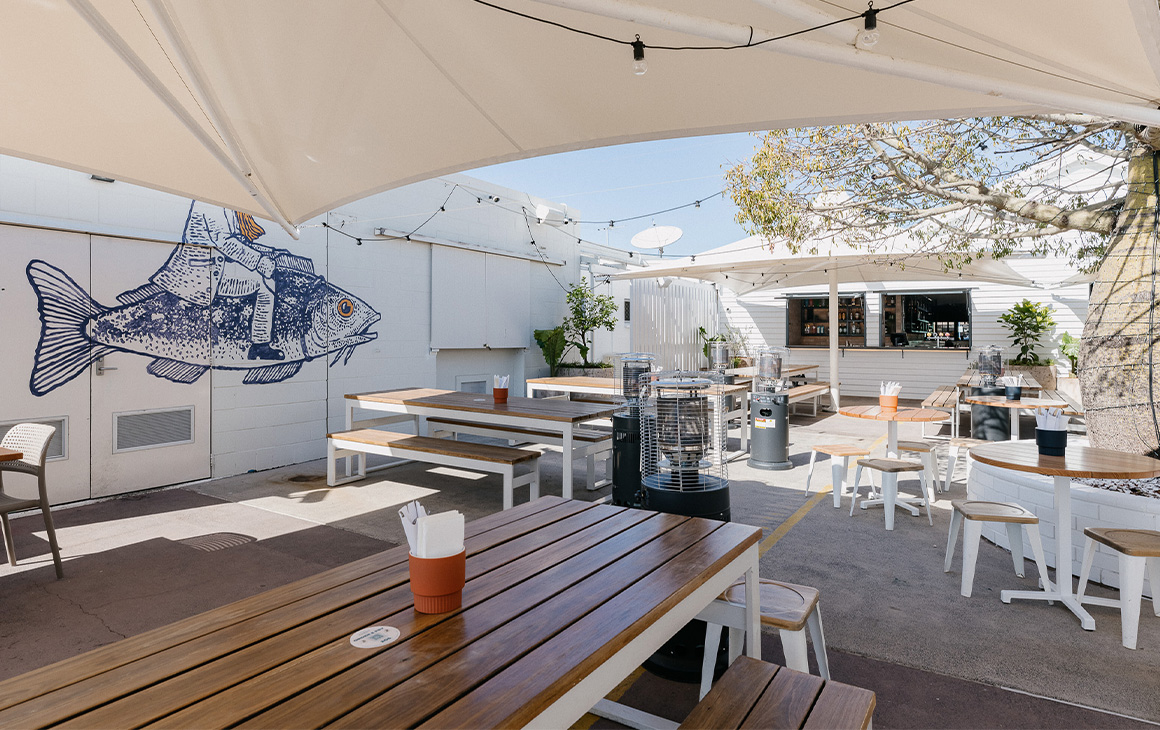 an all-white outdoor seating area at Cleveland Sands, a Brisbane pub
