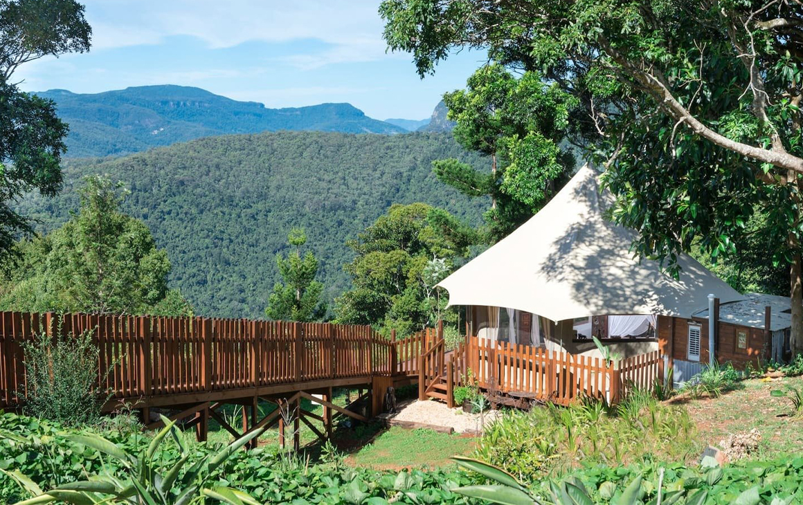 A white, tent looking cabin overlooking mountains.