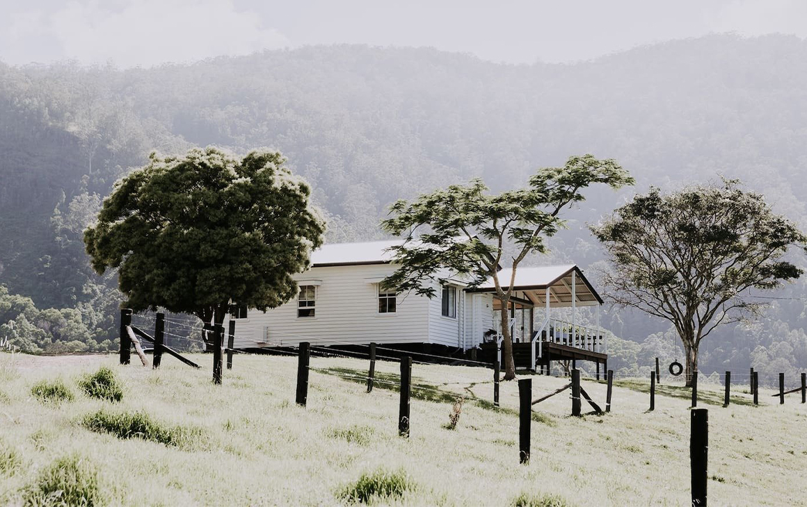 A white cottage in the middle of a farm paddock.