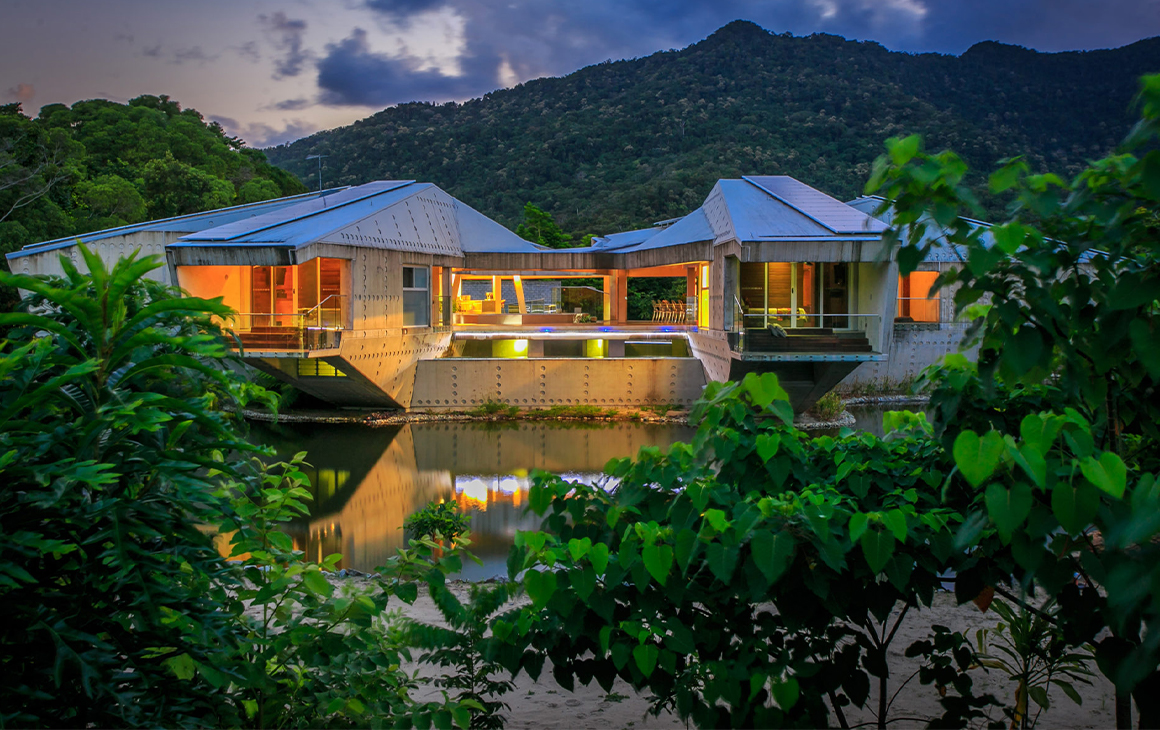 A huge silver lodge with 'wings' stretching out over a lake.