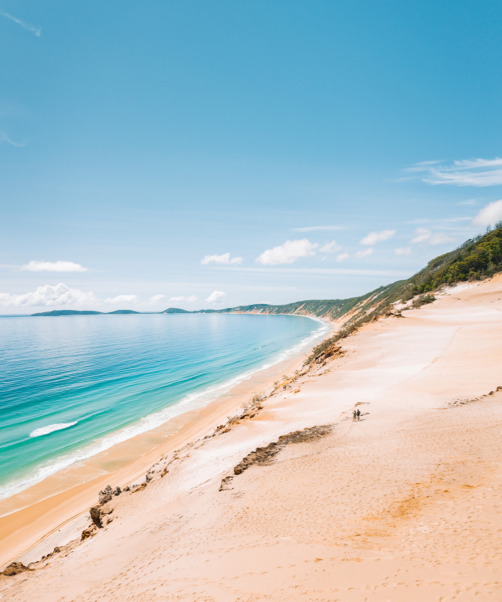 a beautiful long beach with high cliffs stretching into the distance