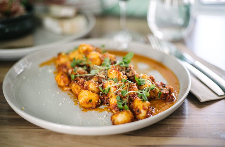 a plate of gnocchi in a tomato based sauce