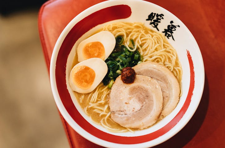a bowl of ramen with pork on top