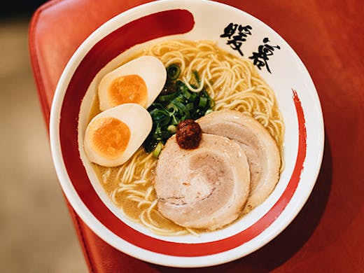 A bowl of ramen topped with pork and eggs