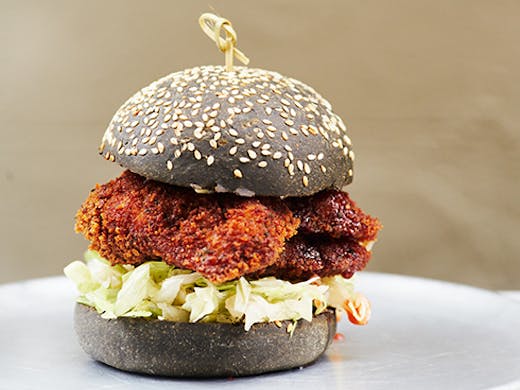 a chicken burger with a charcoal bun