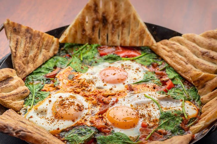 A plate of shakshuka served with triangles of toast for dipping. 