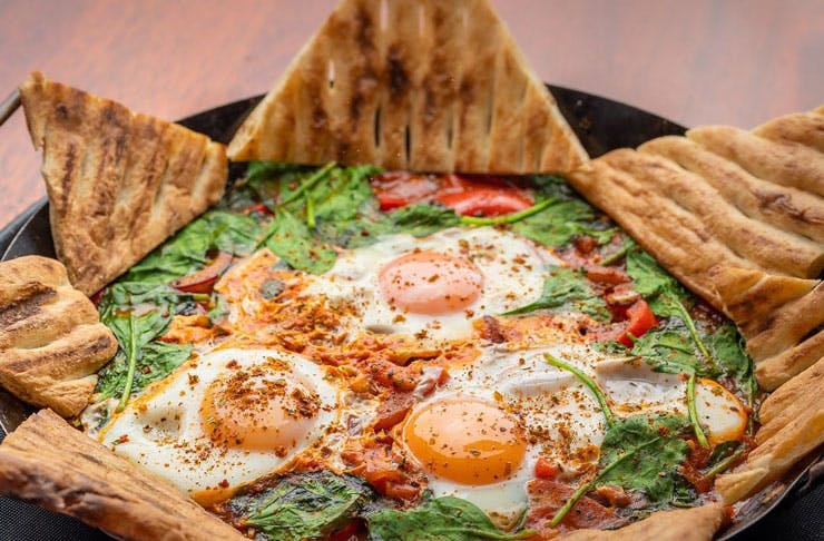 A plate of shakshuka served with triangles of toast for dipping. 