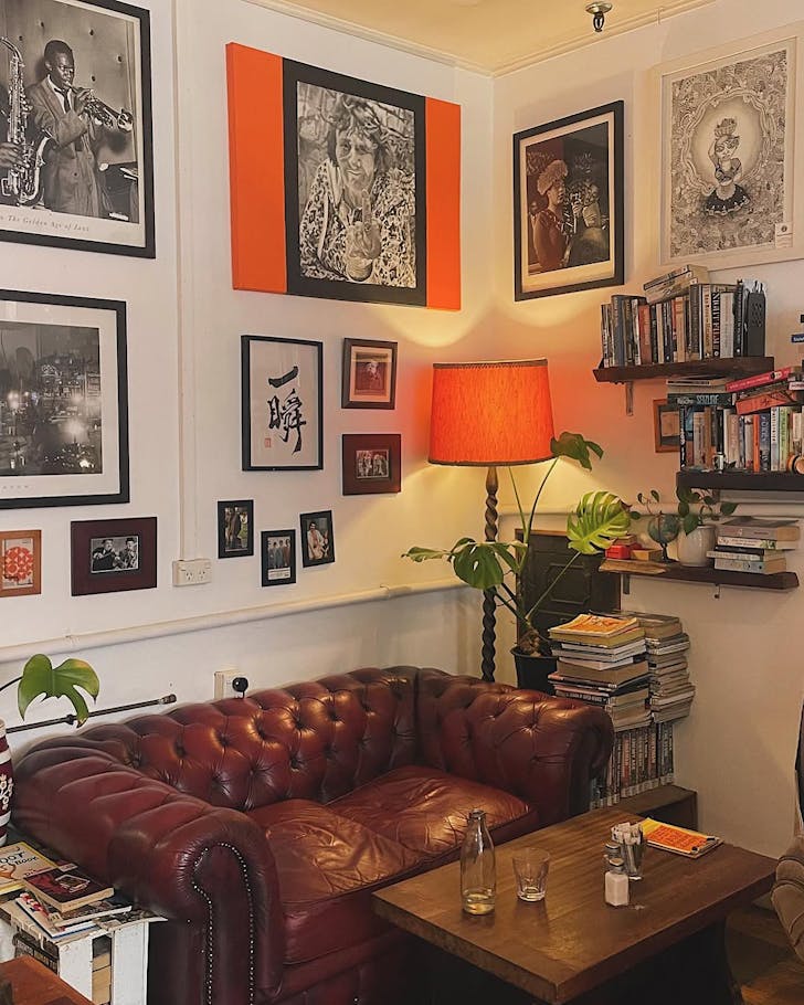 A cosy Remedy Coffee corner with a leather couch and books.