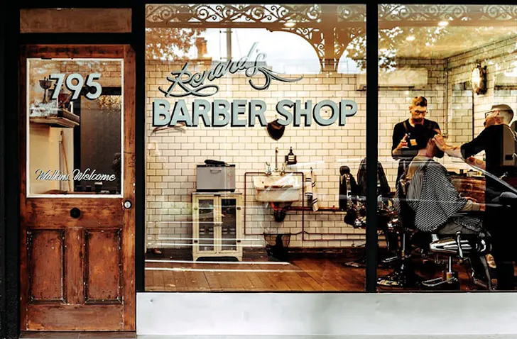 An old school barbershop with a sign on the window that reads 