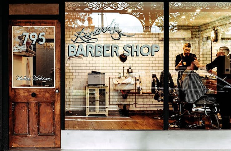 An old school barbershop with a sign on the window that reads 