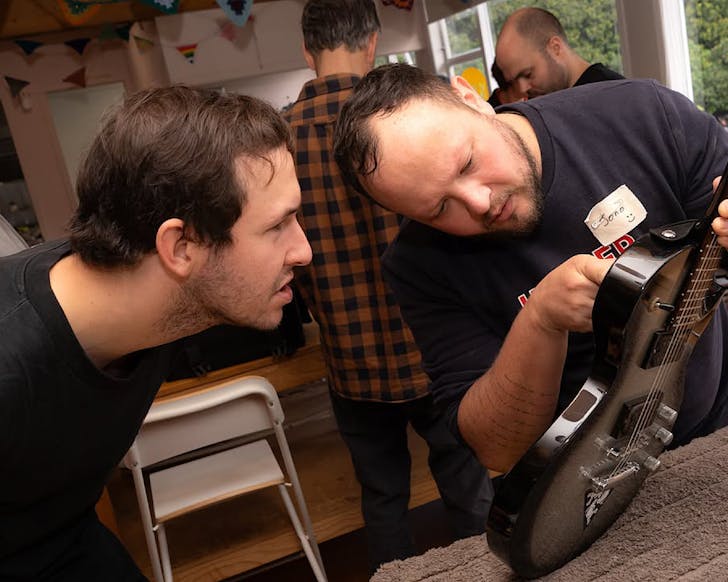 A Repair CafÃ© expert helps someone fix an electric guitar.